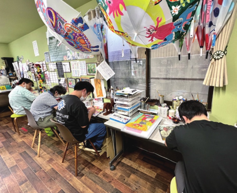 傘の作品が飾られたnestDesignのアトリエで制作する利用者たち